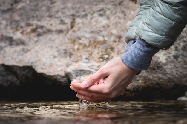 Close-up di mani che raccolgono acqua pulita un uomo attira acqua grezza dal lago il concetto di