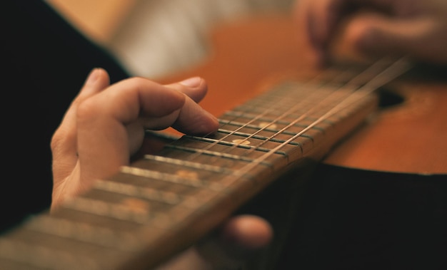 Close-up di mani che suonano la chitarra su uno sfondo sfocato