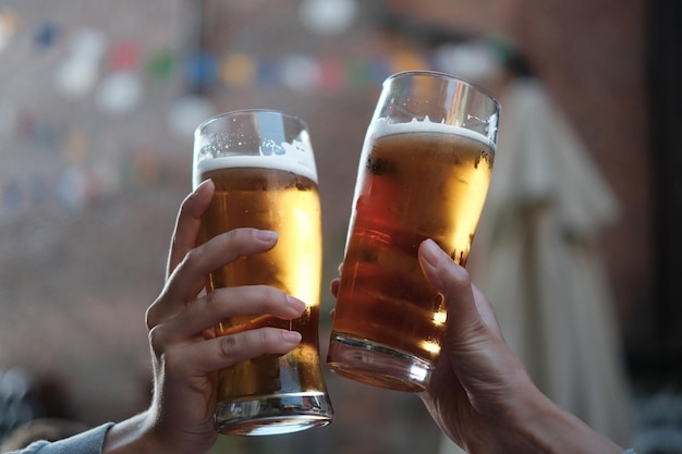 Close-up di mani che tengono bicchieri di birra