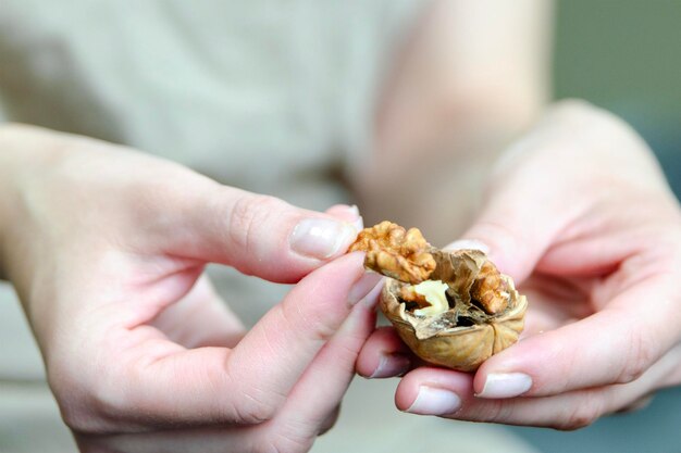 Close-up di mani di una donna che tirano fuori una noce dallo spuntino del guscio su noci sane vista laterale