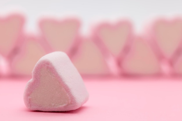 Close-up di marshmallows a forma di cuore rosa sul tavolo su sfondo bianco