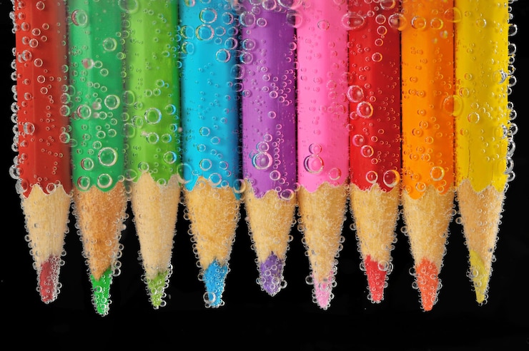 Foto close-up di matite multicolori in acqua contro uno sfondo nero