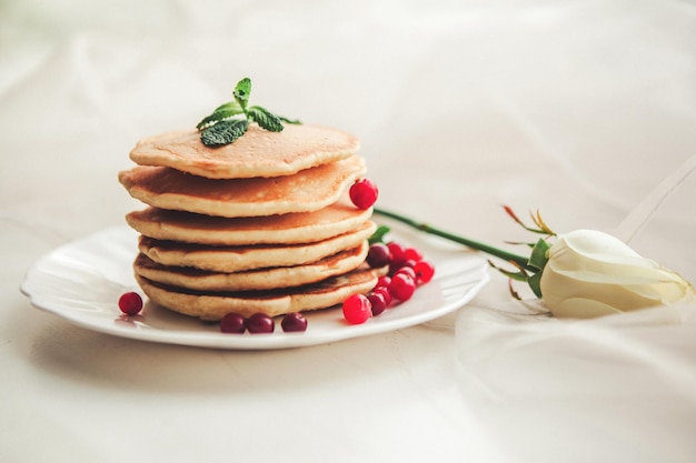 Close-up di pancake con frutta e rose su tessuto