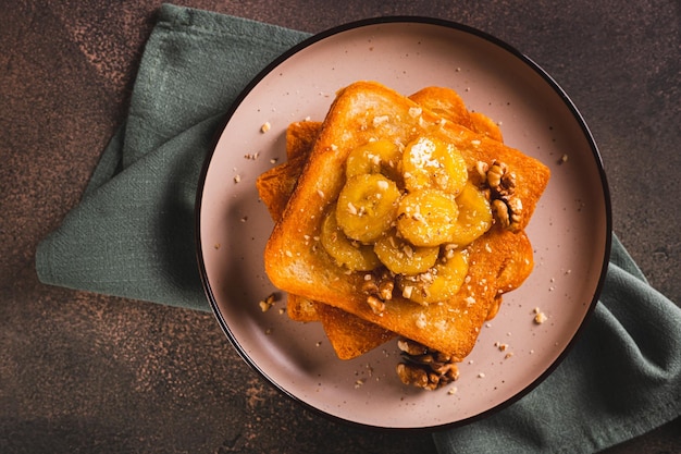 Close-up di pane tostato con miele di banana caramellato e noci per la colazione sulla vista del tavolo