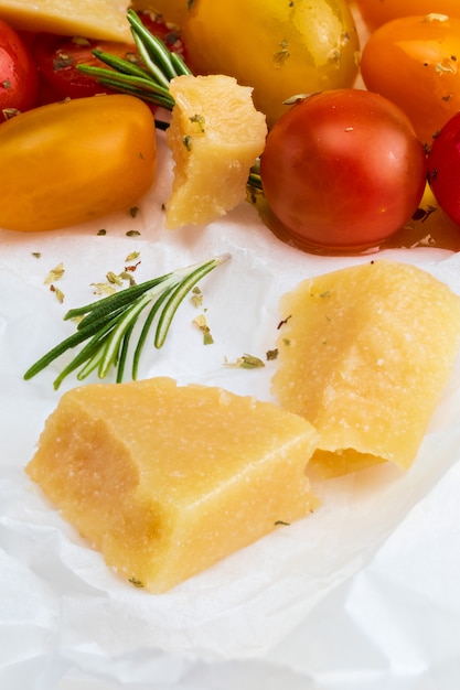 Close-up di pecorino con rosmarino e pomodorini (rosso, granato e giallo), freschi e crudi.