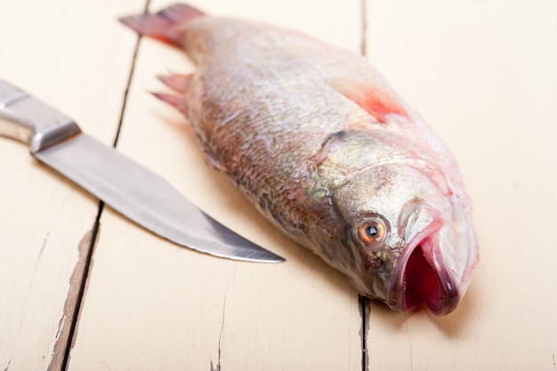 Close-up di pesce crudo e coltello sul tavolo
