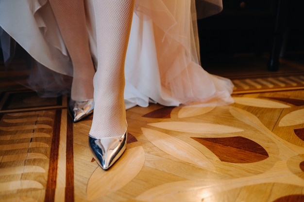 Close-up di scarpe da donna e l'orlo di un abito da sposa. Il piede della sposa in una scarpetta d'argento.