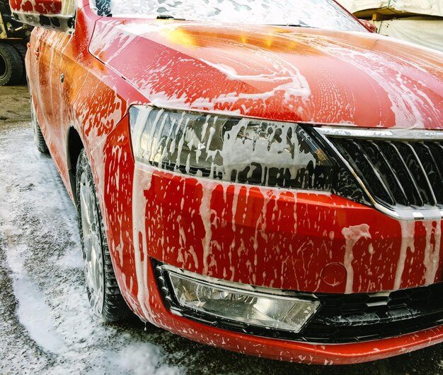 Close-up di schiuma di sapone su un'auto rossa