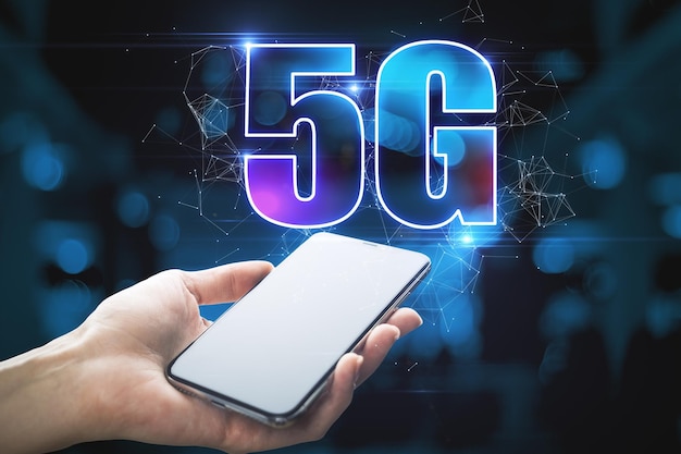 Close up di smartphone in mano con ologramma 5G luminoso astratto su sfondo blu scuro Informazione wireless e concetto di tecnologia futura