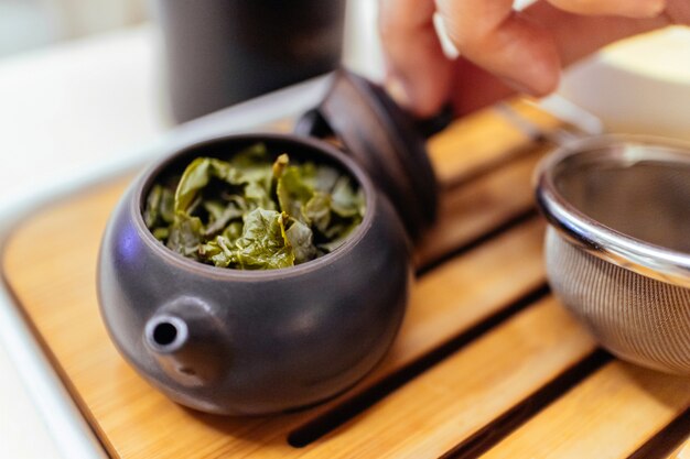 Close-up di tè verde cinese con acqua calda all'interno del piccolo bollitore in ceramica in una tazzina per fare il tè verde.