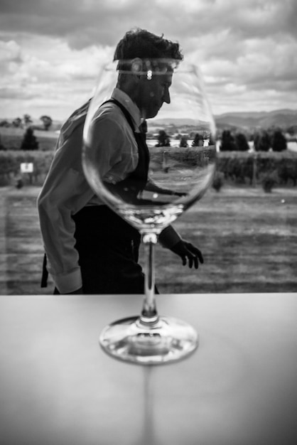 Close-up di un bicchiere di vino con un uomo che cammina sul paesaggio