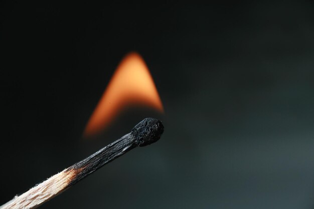 Close-up di un fiammifero in fiamme su sfondo nero