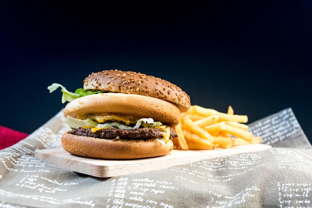 Close-up di un hamburger e delle patatine fritte su uno sfondo nero