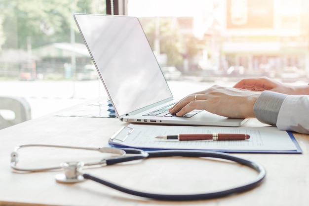 Close-up di un medico che usa un portatile sul tavolo