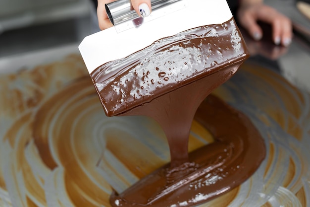 Close-up di un pasticcere utilizzando spatole tempera cioccolato fuso