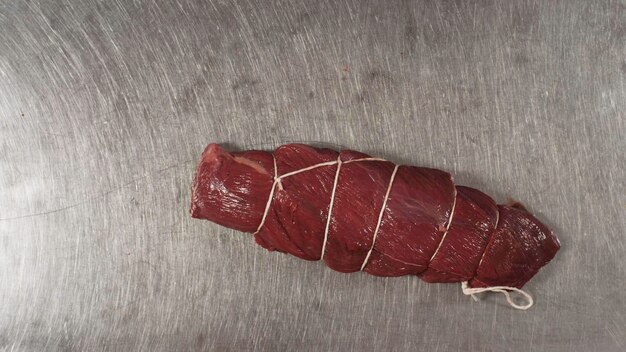 Close up di un pezzo di carne rossa fresca vista dall'alto di un pezzetto di carne legato con una corda da cibo