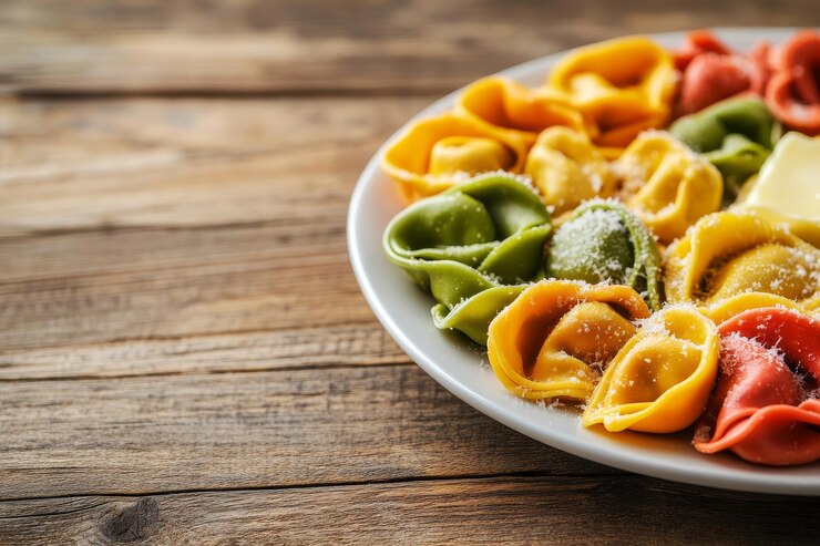 Foto close-up di un piatto di tortellini colorati disposti in cerchio su un tavolo di legno i tortelli