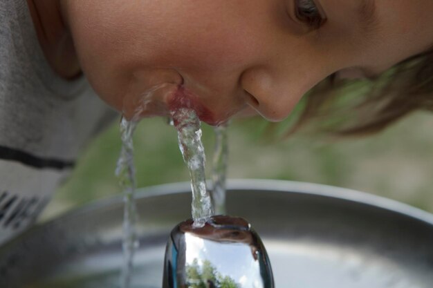 Close-up di un ragazzo che beve acqua dal rubinetto