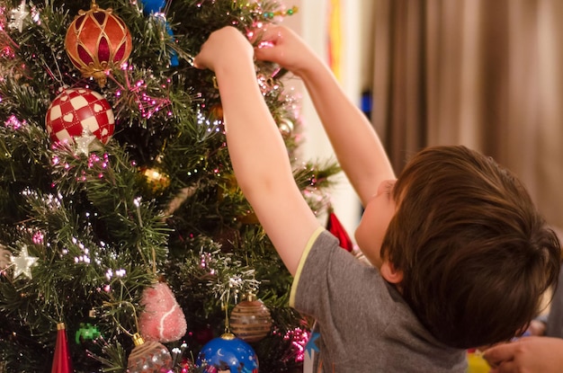 Close-up di un ragazzo che decora l'albero di Natale a casa