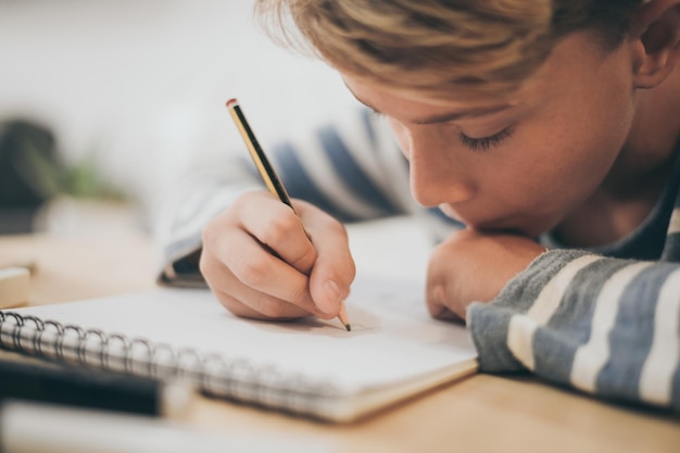 Close-up di un ragazzo che scrive un libro al tavolo