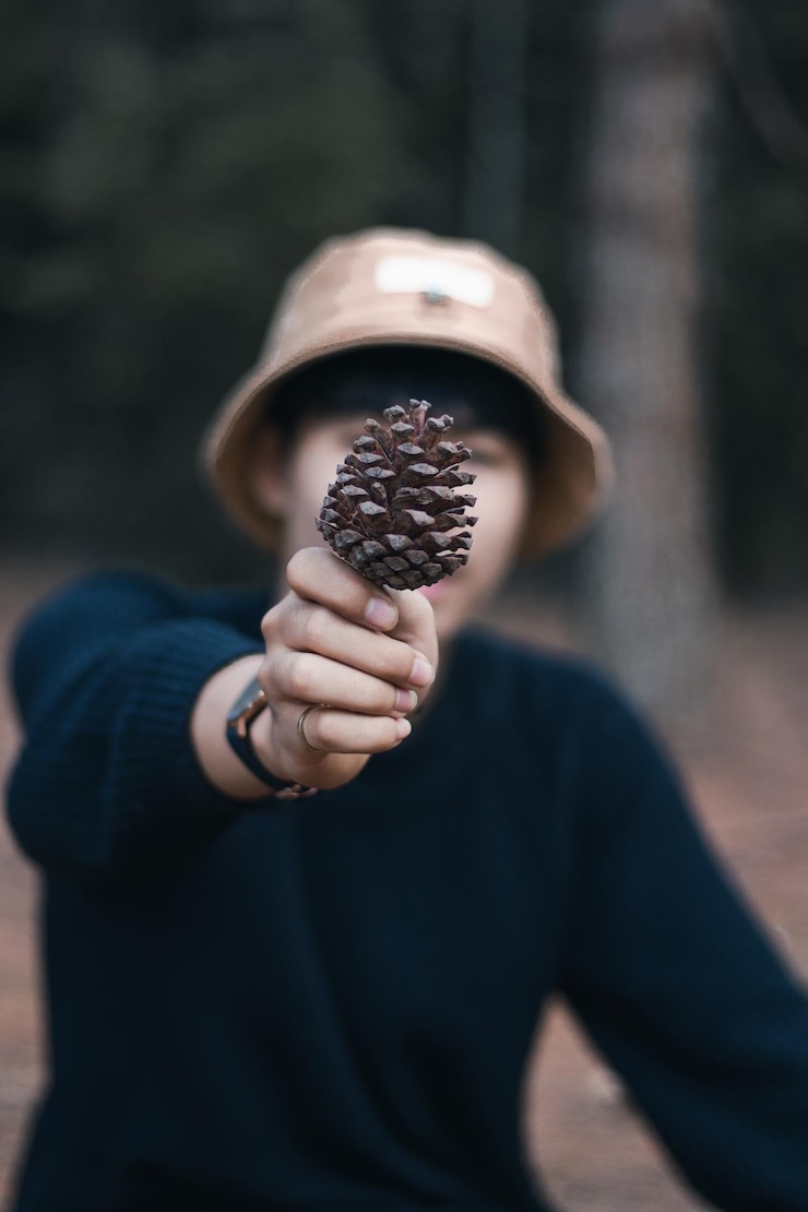 Foto close-up di un uomo che copre la faccia con una cono di pino