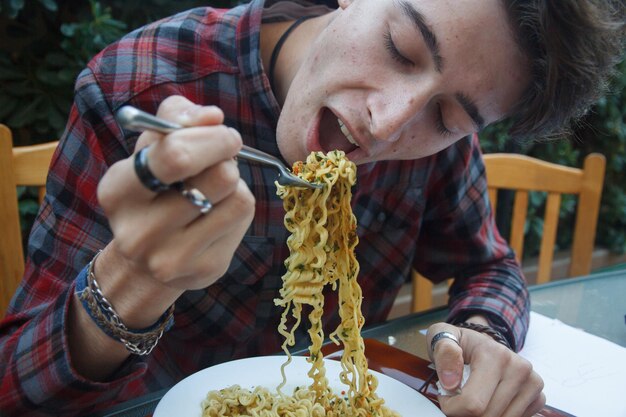 Close-up di un uomo che mangia noodles a tavola