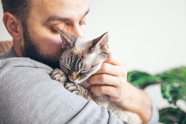 Close-up di un uomo con un gatto con gli occhi chiusi