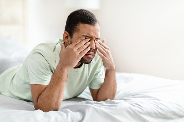 Close-up di un uomo nero sconvolto sdraiato a letto a piangere
