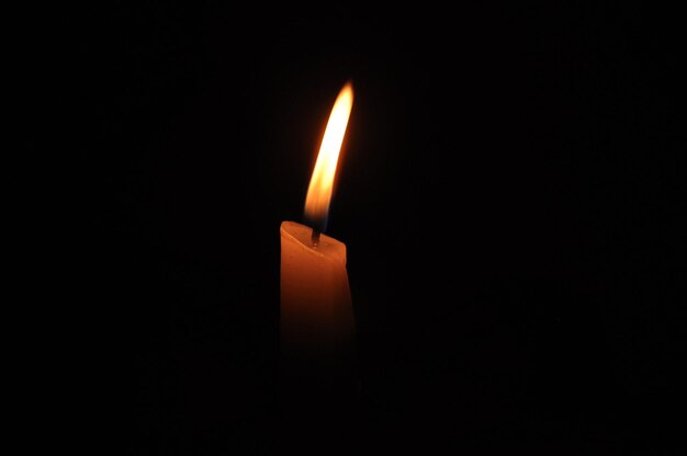 Close-up di una candela accesa in camera oscura