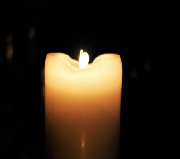 Close-up di una candela accesa in camera oscura