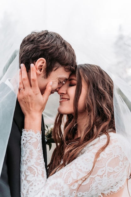Close-up di una coppia di sposi con gli occhi chiusi che fanno l'amore sotto il velo