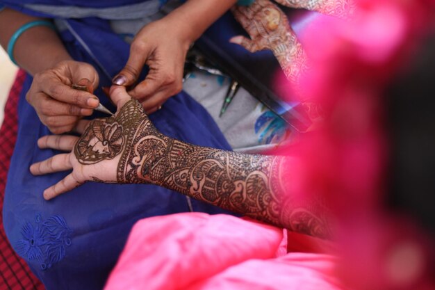 Close-up di una donna che applica un tatuaggio di henna sulla mano