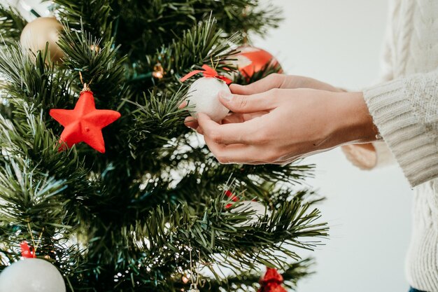 Close-up di una donna che decora l'albero di Natale a casa