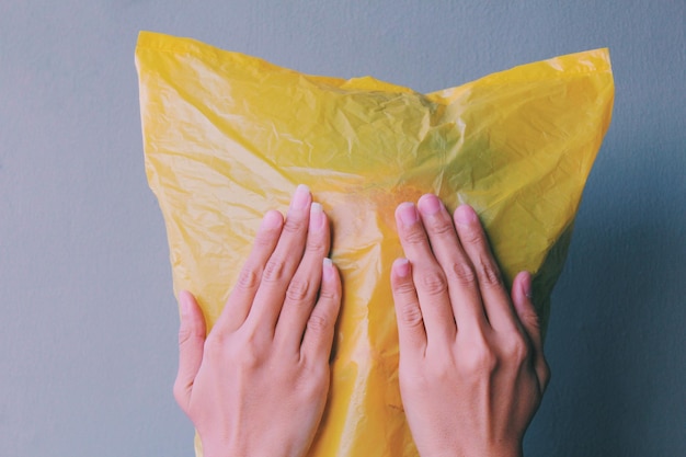 Close-up di una donna che indossa un sacchetto di plastica giallo sul viso vicino alla parete