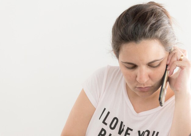 Close-up di una donna che parla al cellulare su uno sfondo bianco