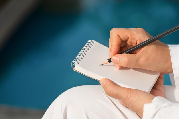 Close-up di una donna che scrive su un taccuino con una matita