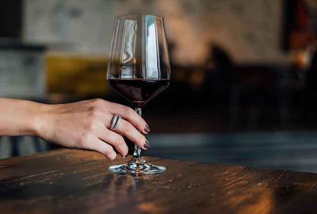 Close-up di una donna che tiene un bicchiere di vino rosso sul tavolo