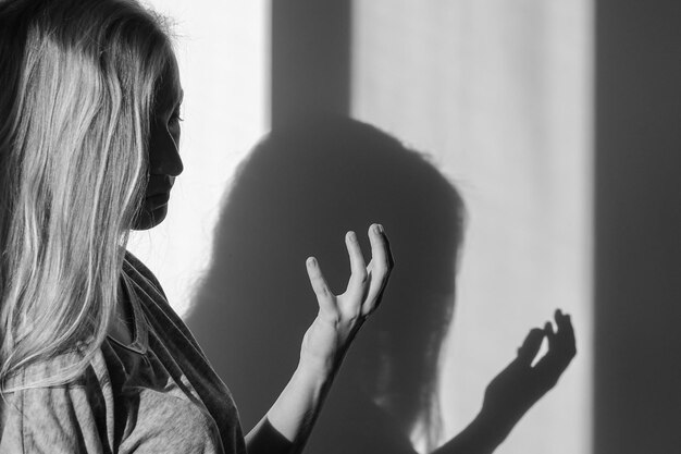 Close-up di una donna con l'ombra sul muro a casa