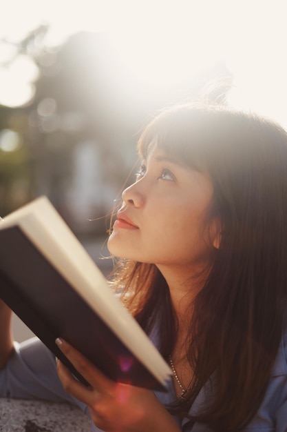 Close-up di una donna con un libro all'aperto