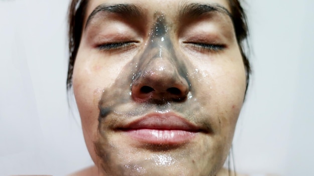 Close-up di una donna con una maschera facciale su uno sfondo bianco