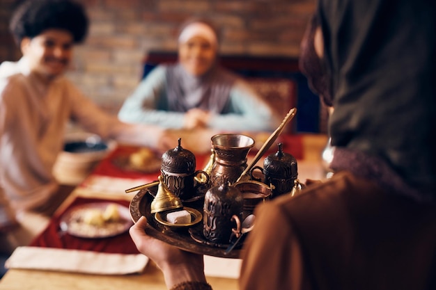Close-up di una donna musulmana tradizionale che serve caffè turco a casa
