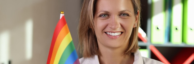 Close-up di una dottoressa sorridente che tiene in mano la bandiera dell'arcobaleno