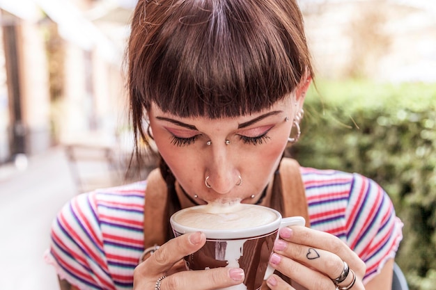 Close-up di una giovane donna che beve caffè in un caffè all'aperto