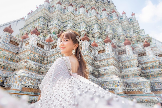 Close up di una giovane donna che indossa un abito tradizionale thailandese con accessori in piedi a Wat Arun un luogo popolare per i turisti di tutto il mondo Bangkok Thailandia