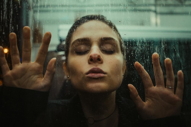 Close-up di una giovane donna che tocca la finestra di vetro