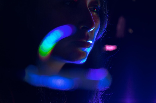 Close-up di una giovane donna contro apparecchiature di illuminazione illuminate