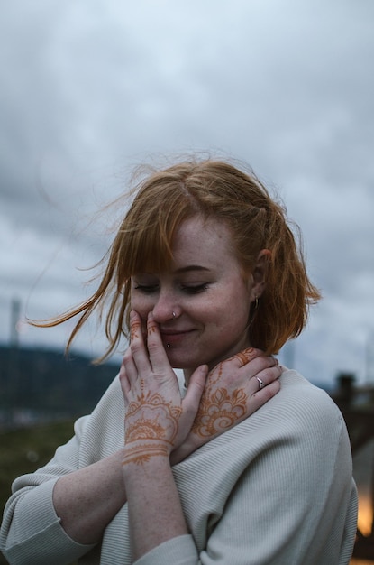 Close-up di una giovane donna sorridente in piedi contro un cielo nuvoloso