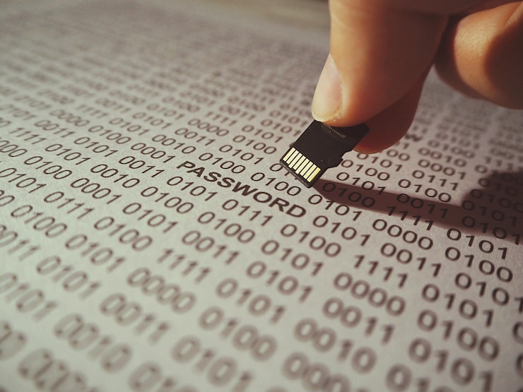 Foto close-up di una mano che tiene un chip di computer sopra il testo della password in un libro