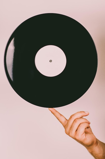 Close-up di una mano che tiene un disco in vinile su uno sfondo rosa