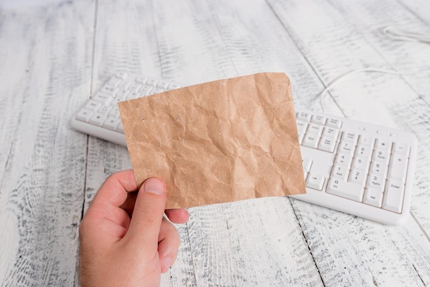 Close-up di una mano che tiene una carta marrone sopra la scrivania.